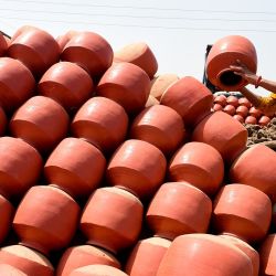 Un alfarero apila vasijas de arcilla que se utilizan popularmente para almacenar agua potable durante la estación estival, en un pueblo de las afueras de Ahmedabad, India. | Foto:SAM PANTHAKY / AFP