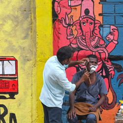 Un hombre se deja afeitar por un barbero al borde de la carretera en Bombay, India. | Foto:INDRANIL MUKHERJEE / AFP