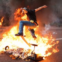Un manifestante pasa con un monopatín por encima de contenedores de basura en llamas durante una manifestación después de que el gobierno impulsara una reforma de las pensiones a través del parlamento sin votación, utilizando el artículo 49.3 de la Constitución, en Toulouse, sur de Francia. | Foto:CHARLY TRIBALLEAU / AFP