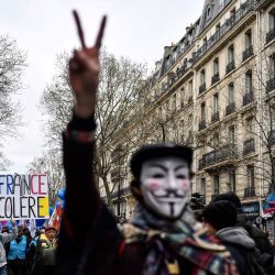 Un manifestante sostiene una pancarta en la que se lee "Francia en cólera" mientras otro con una máscara de Guy Fawkes hace el gesto de la V durante una manifestación después de que el gobierno impulsara una reforma de las pensiones a través del parlamento sin votación, utilizando el artículo 49.3 de la Constitución, en París. | Foto:JULIEN DE ROSA / AFP