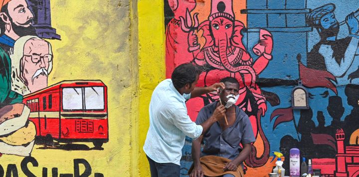 Un hombre se deja afeitar por un barbero al borde de la carretera en Bombay, India.