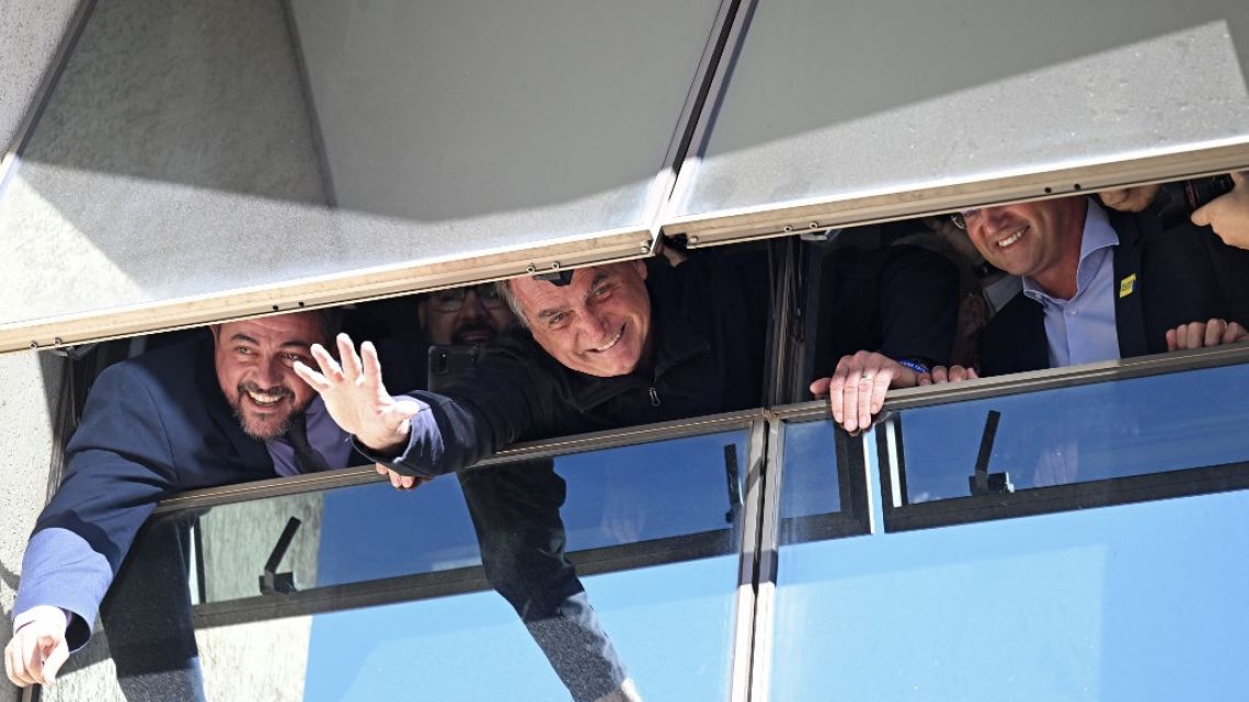 Former Brazilian President Jair Bolsonaro greets supporters from a window at the Liberal Party headquarters in Brasilia on March 30, 2023. 