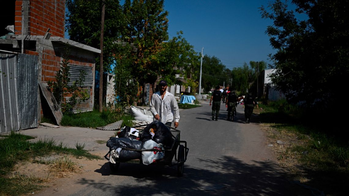 A man pushes a cart while members of National Gendarmerie patrol a street in the Los Pumitas neighbourhood in Rosario, Santa Fe Province, Argentina, on March 15, 2023.