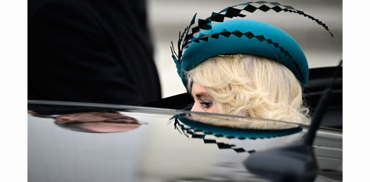 La reina consorte británica Camilla y su sombrero se reflejan en el casco de un coche mientras sale tras una visita al palacio presidencial de Bellevue en Berlín.