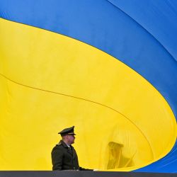 Militares ucranianos sostienen la enorme bandera nacional antes de izarla al mástil durante una ceremonia que conmemora el primer aniversario de la retirada de las tropas rusas de la ciudad ucraniana de Bucha, en Bucha, cerca de Kiev. | Foto:SERGEI SUPINSKY / AFP