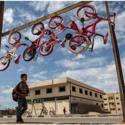 Un alumno vuelve a casa pasando por delante de una tienda de bicicletas en la ciudad de Gaza. | Foto:MOHAMMED ABED / AFP