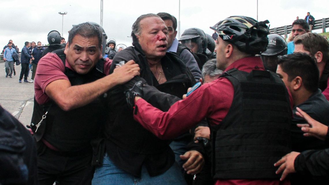 Buenos Aires Province Security Minister Sergio Berni (centre) is taken away by police officers after being beaten by a group of bus drivers protesting for the murder of a colleague in La Matanza, on the western outskirts of Buenos Aires, on April 3, 2023. 