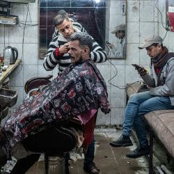 En esta imagen un barbero corta el pelo a un hombre en un salón tradicional en la zona empobrecida de Zabalin de El Cairo, Egipto. | Foto:AMIR MAKAR / AFP