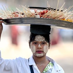 En esta imagen una mujer lleva una bandeja de comida con la cabeza durante el festival de la pagoda Mann Shwe Sat Thaw en el municipio de Minn Buu, Myanmar. | Foto:AFP