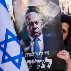 Una manifestante se cubre la cara con un cartel contra el primer ministro israelí, Benjamin Netanyahu, durante una marcha contra el proyecto de ley de reforma judicial del Gobierno, en Tel Aviv. | Foto:JACK GUEZ / AFP