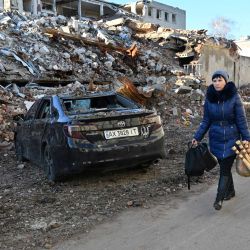 Una residente local lleva la compra mientras pasa por delante de un edificio destruido tras el impacto de un misil C-300 en la ciudad ucraniana de Kharkiv. | Foto:SERGEY BOBOK / AFP