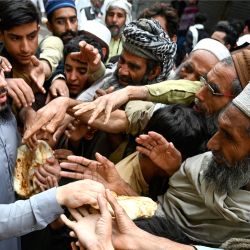 Unos hombres recogen pan gratuito en un punto de distribución de Peshawar. - Los paquistaníes pobres se están llevando la peor parte de la crisis económica, y al menos 20 personas han muerto desde el comienzo del mes de ayuno musulmán del Ramadán en aglomeraciones en centros de distribución de alimentos. | Foto:ABDUL MAJEED / AFP