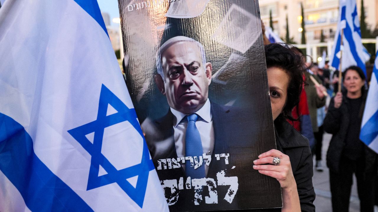 Una manifestante se cubre la cara con un cartel contra el primer ministro israelí, Benjamin Netanyahu, durante una marcha contra el proyecto de ley de reforma judicial del Gobierno, en Tel Aviv. | Foto:JACK GUEZ / AFP