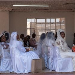 Un grupo de novias esperan en la Iglesia de la Santidad Pentecostal Internacional de Zuurbekom, al sur de Johannesburgo, mientras participan en una ceremonia nupcial multitudinaria en la que se casaron 80 parejas. | Foto:IHSAAN HAFFEJEE / AFP