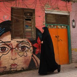 Mujeres iraquíes caminan junto a obras de arte pintadas en casas del barrio de al-Anbari, en Bagdad. - El grupo de artistas iraquíes Al-farasha ha estado pintando murales inspirados en el folclore tradicional en las estrechas callejuelas de los antiguos barrios bagdadíes. | Foto:AHMAD AL-RUBAYE / AFP