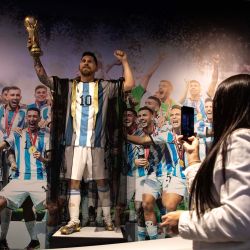 Una mujer toma una fotografía a una estatua de Lionel Messi en la Copa Mundial de Qatar 2022 durante la exposición oficial de la Asociación del Fútbol Argentino "Campeones del Mundo" en el predio ferial La Rural, en Buenos Aires. | Foto:Xinhua/Martín Zabala