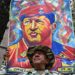 Un miembro de la milicia bolivariana sostiene una pintura con la imagen del fallecido presidente venezolano Hugo Chávez (1999-2013) durante una marcha para conmemorar el 21 aniversario del regreso de Chávez al poder tras el fallido golpe de 2002, en Caracas. | Foto:YURI CORTEZ / AFP