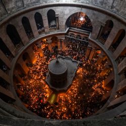 Cristianos ortodoxos se reúnen con velas encendidas alrededor del Edículo, tradicionalmente considerado el lugar de enterramiento de Jesucristo, durante la ceremonia del Fuego Sagrado en la iglesia del Santo Sepulcro, en la Ciudad Vieja de Jerusalén. | Foto:RONALDO SCHEMIDT / AFP