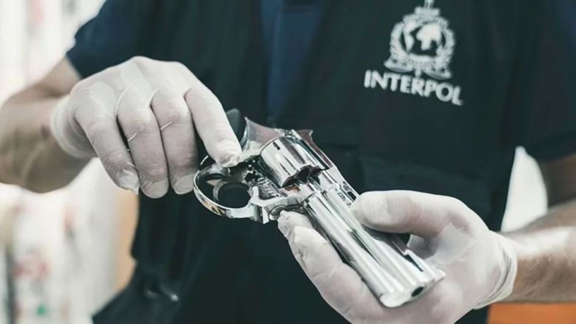 Stock image of Interpol employee handling a seized gun.