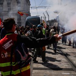 Un manifestante sostiene una bengala roja mientras los manifestantes bloquean el paso del tranvía durante una manifestación contra la recién firmada reforma de las pensiones, en Burdeos, suroeste de Francia. | Foto:THIBAUD MORITZ / AFP