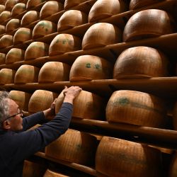 Un trabajador gira una rueda de queso Parmigiano Reggiano en el departamento de maduración de la Casearia Castelli, miembro del Grupo Lactalis, en el Caseificio Tricolore en Reggio Emilia, norte de Italia. | Foto:MARCO BERTORELLO / AFP