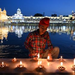 Un devoto sij enciende una lámpara de aceite con motivo del aniversario del nacimiento del segundo gurú sij Angad Dev, en el Templo Dorado iluminado de Amritsar. | Foto:Narinder Nanu / AFP