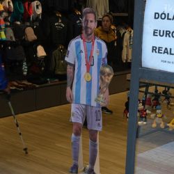 Un cartel con los valores de cambio de moneda del llamado "Dólar Blue" no oficial, se muestra en la vidriera de una tienda en Buenos Aires cerca de una figura de cartón de la estrella del fútbol argentino Lionel Messi. | Foto:JUAN MABROMATA / AFP