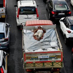 Un trabajador duerme en la parte trasera de un camión de reparto mientras los vehículos están atrapados en el tráfico en la autopista Western Express en Mumbai, India. | Foto:INDRANIL MUKHERJEE / AFP