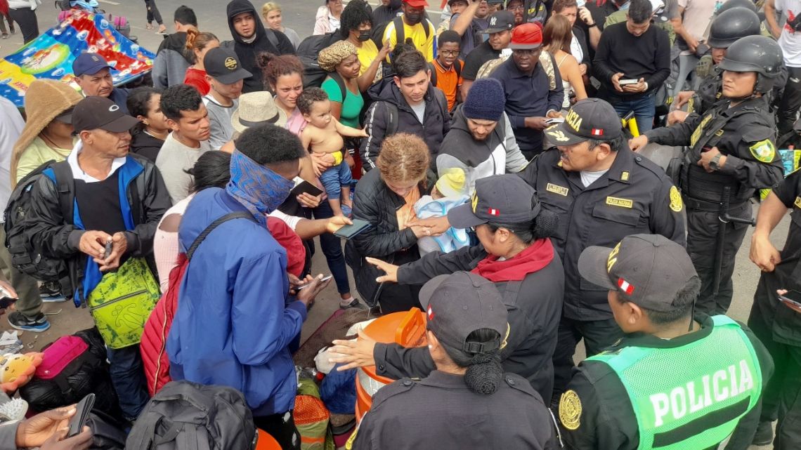Peruvian police officers prevent migrants of various nationalities who remain stranded in the no-man's land in the border between Peru and Chile, from entering Peru, near the southern Peruvian city of Tacna, on April 26, 2023.