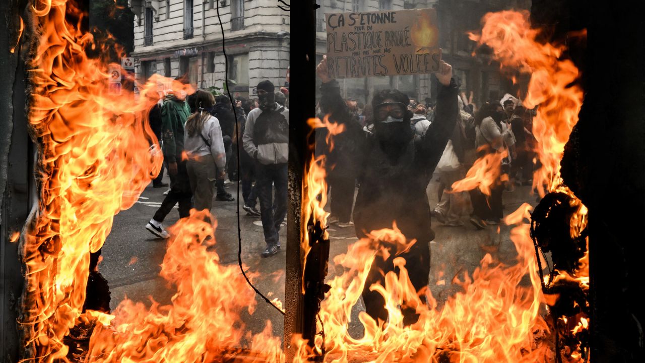Un manifestante sostiene un cartel en el que se puede leer "Asfixiados por el plástico quemado, pero no por nuestras pensiones robadas" durante una manifestación un mes después de que el gobierno impulsara una impopular ley de reforma de las pensiones a través del parlamento, en Lyon, este de Francia. | Foto:JEFF PACHOUD / AFP