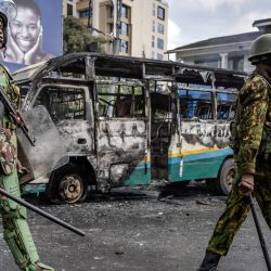 Agentes de policía kenianos caminan junto a un autobús quemado por manifestantes durante los disturbios en Nairobi. | Foto:Luis Tato / AFP
