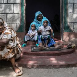 Sadia Aden (izquierda), de 23 años, sentada en la puerta de la casa de su familia mientras sus hijos gemelos, Khalil y Khalid Mukthar, que se están recuperando de los efectos de una desnutrición grave, juegan con su abuela en la ciudad de Garissa, Kenia. | Foto:Tony Karumba / AFP