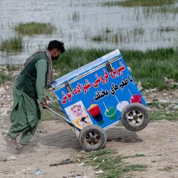 Un vendedor de helados afgano empuja su carrito mientras busca clientes cerca del lago Shuhada, en Kabul. | Foto:WAKIL KOHSAR / AFP