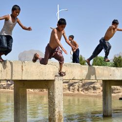 Unos niños saltan a un canal para nadar en las afueras de la provincia de Kandahar, Afganistán. | Foto:Sanaullah Seiam / AFP