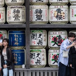 Varias personas se fotografían delante de barriles de sake en el santuario de Tsuruoka Hachimangu, en la ciudad de Kamakura, Japón. | Foto:YUICHI YAMAZAKI / AFP