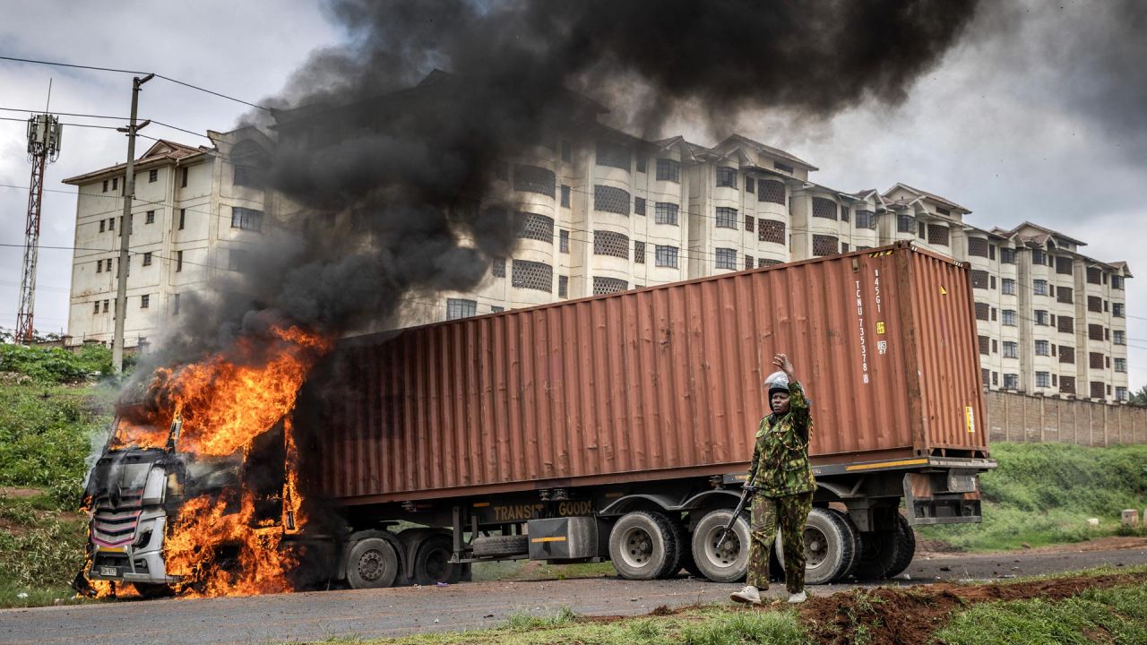 Un agente de policía keniano pide refuerzos frente a un camión incendiado por manifestantes durante los disturbios en el asentamiento informal de Kibera, en Nairobi, Kenia. | Foto:Luis Tato / AFP