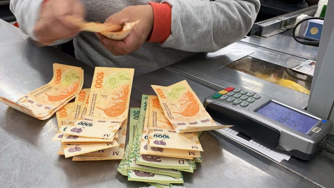 A shop attendant counts out cash at a supermarket in Buenos Aires.