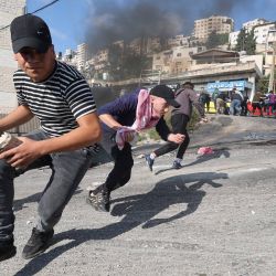 Manifestantes palestinos se cubren en medio de enfrentamientos con las fuerzas de seguridad israelíes durante una redada en el casco antiguo de Nablus, en la Cisjordania ocupada. | Foto:JAAFAR ASHTIYEH / AFP