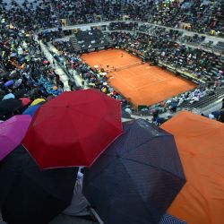 Espectadores en la Pista Central se protegen mientras la lluvia interrumpe la tercera ronda del torneo de tenis masculino ATP Rome Open entre el griego Stefanos Tsitsipas y el italiano Lorenzo Sonego en el Foro Itálico de Roma. | Foto:FILIPPO MONTEFORTE / AFP