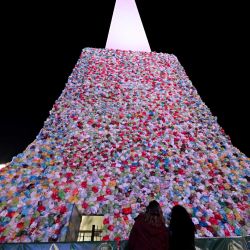 Mujeres observan el Obelisco cubierto de bolsas de plástico como parte de una intervención artística en vísperas del Día Mundial del Reciclaje en Buenos Aires. | Foto:LUIS ROBAYO / AFP