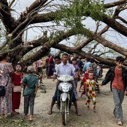 Tras el paso del ciclón Mocha por Kyauktaw, en el estado de Rakhine (Myanmar), algunos residentes caminan junto a árboles caídos. El ciclón Mocha tocó tierra en Myanmar y el sudeste de Bangladesh, arrancando árboles, destruyendo viviendas precarias en los campos de desplazados rohingya y provocando mareas de tempestad en las zonas bajas. | Foto:Sai Aung Main / AFP