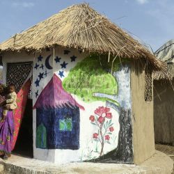 En esta foto Champa Chanbeli, que enseña a otros a fabricar cocinas de tierra levantadas del suelo, sale de su choza resistente a las inundaciones en la aldea de Sanjar Chang, en el distrito de Tando Allahyar. A sus 82 años, la arquitecta Yasmeen Lari está abriendo camino en la fortificación de las comunidades rurales de Pakistán, que viven en primera línea del cambio climático. Los pocos asentamientos piloto ya construidos han salvado a las familias de lo peor de las catastróficas inundaciones monzónicas que el año pasado anegaron un tercio del país. | Foto:ASIF HASSAN / AFP