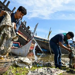 Estudiantes universitarios limpian plásticos y otros desechos arrastrados por la corriente en un puerto de Banda Aceh, Indonesia. | Foto:CHAIDEER MAHYUDDIN / AFP