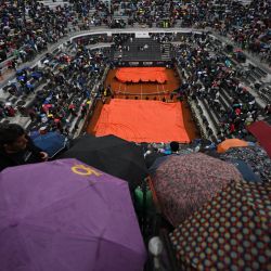 La pista central se cubre con una lona mientras comienza a llover antes de la final del torneo de tenis masculino ATP Rome Open entre el danés Holger Rune y el ruso Daniil Medvedev, en la pista central del Foro Itálico de Roma. | Foto:FILIPPO MONTEFORTE / AFP