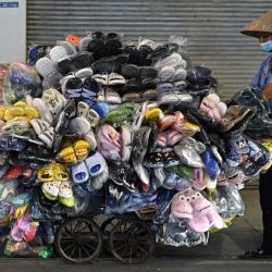 La foto muestra a un vendedor ambulante empujando un carrito de zapatos y zapatillas en Hanoi. | Foto:NHAC NGUYEN / AFP