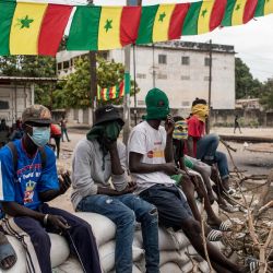 Manifestantes sentados sobre barricadas de sacos de arena mientras bloquean la carretera que lleva a la casa del líder de la oposición Ousmane Sonko en Ziguinchor, Senegal. Los manifestantes han estado bloqueando las carreteras en Ziguinchor para impedir la detención del líder de la oposición Ousmane Sonko antes de su juicio por violación. | Foto:MUHAMADOU BITTAYE / AFP