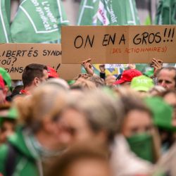 Un manifestante sostiene una pancarta en la que se lee "estamos hartos de los accionistas" durante una manifestación convocada por los sindicatos belgas contra el dumping social y para denunciar los ataques al derecho de huelga, en Bruselas. | Foto:LAURIE DIEFFEMBACQ / Belga / AFP