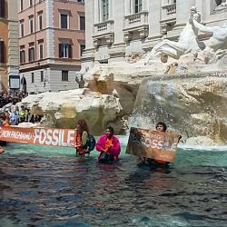 Una foto tomada y difundida por activistas ecologistas de Última Generación muestra a un activista del grupo sosteniendo una pancarta en la que se lee "no pagamos por los fósiles" en la histórica Fontana di Trevi de Roma, después de que los activistas vertieran en el agua líquido negro hecho a base de carbón vegetal como parte de una campaña para concienciar sobre el cambio climático. | Foto:Handout / LAST GENERATION / AFP