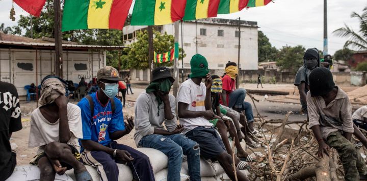 Manifestantes sentados sobre barricadas de sacos de arena mientras bloquean la carretera que lleva a la casa del líder de la oposición Ousmane Sonko en Ziguinchor, Senegal. Los manifestantes han estado bloqueando las carreteras en Ziguinchor para impedir la detención del líder de la oposición Ousmane Sonko antes de su juicio por violación.