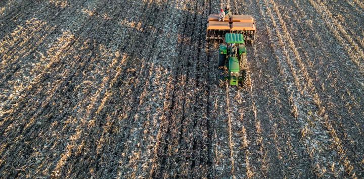 Toma aérea de trabajadores agrícolas utilizando un tractor para plantar semillas de centeno en la granja Merrydale, a las afueras de Frankfort.
